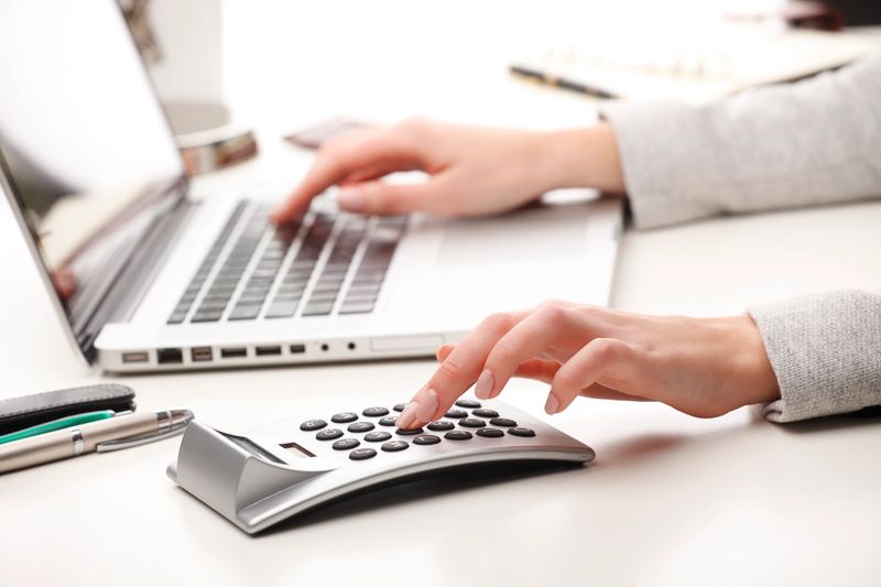 A lady calculating a mortgage with a laptop and calculator on her desk